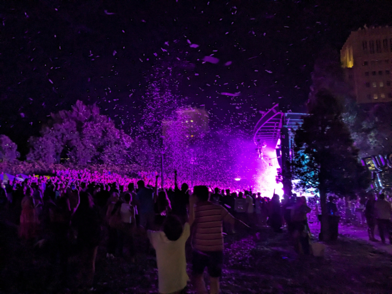 Festival-goers celebrating under confetti and purple lights during a nighttime performance in Salt Lake City.
